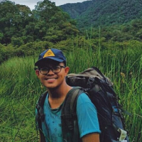 Language activist Fikri Ansori, smiling during a hiking trip. He carries a small backpack.