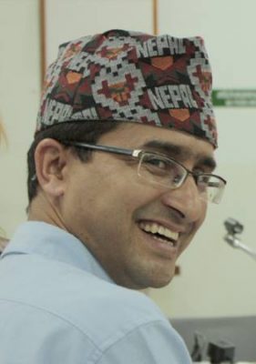 Pushker Kadel, a development specialist from Nepal, in an embroidered hat with the word "Nepal" on it.